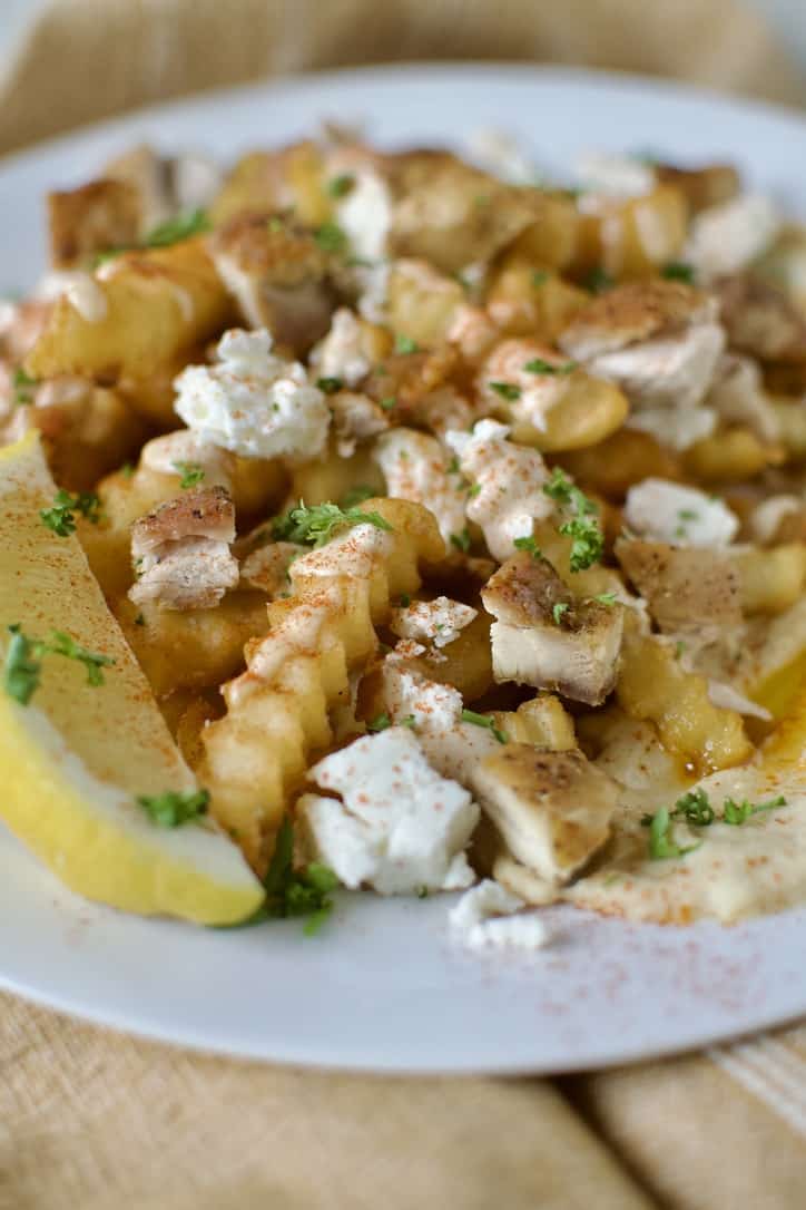 Greek Fries assembled nacho style on a white plate, ready to eat.