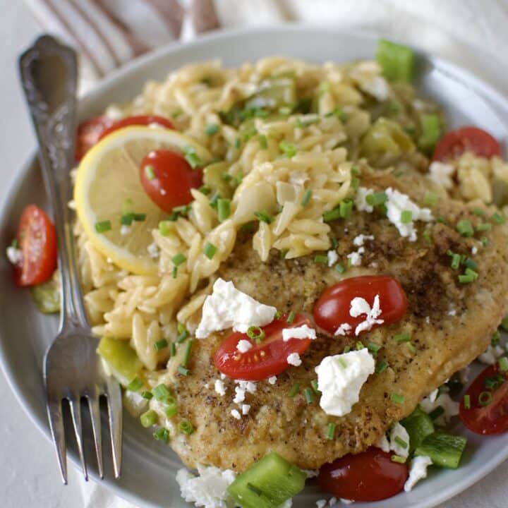 Lemon Orzo Chicken with Feta and Tomatoes finished and ready to eat, on a plate.