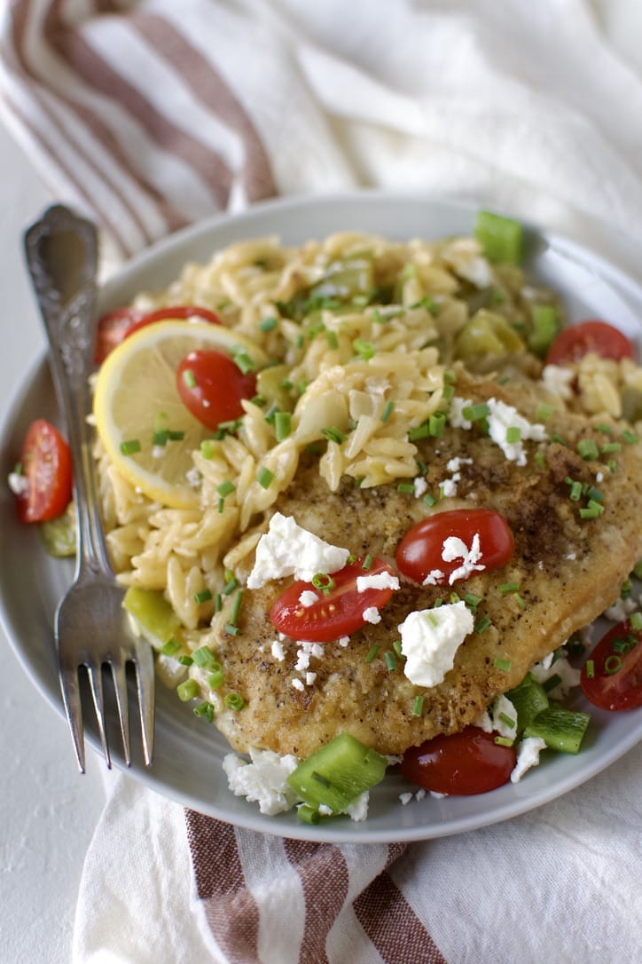 Lemon Orzo Chicken with Feta and Tomatoes finished and ready to eat, on a plate.