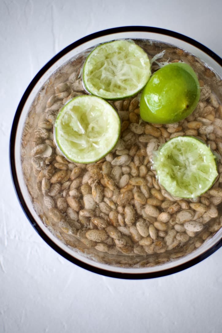 Soaking pinto beans in water with baking soda, and lime juice and wedges.