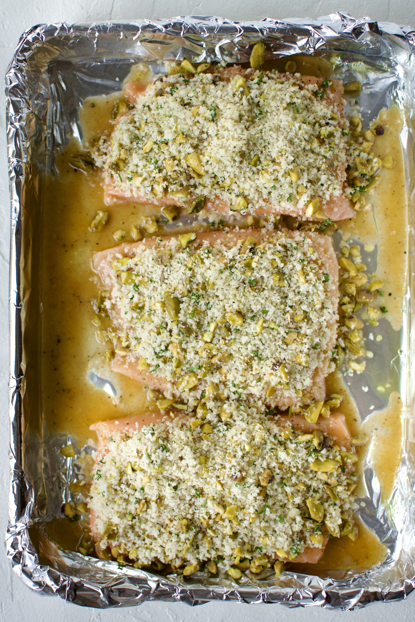 Salmon fillets topped with the pistachio crust ready to be baked.