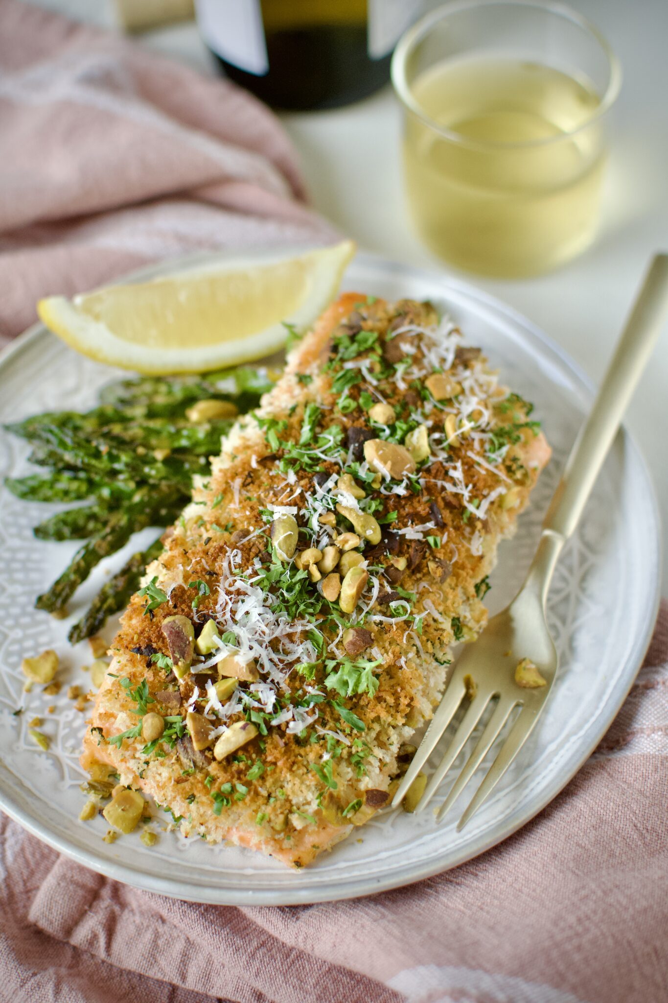 Pistachio Crusted Salmon on a plate with some grilled asparagus and a lemon wedge. Ready to eat.