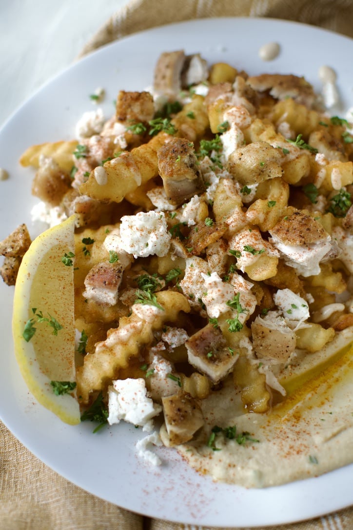 Greek Fries assembled nacho style on a white plate, ready to eat.