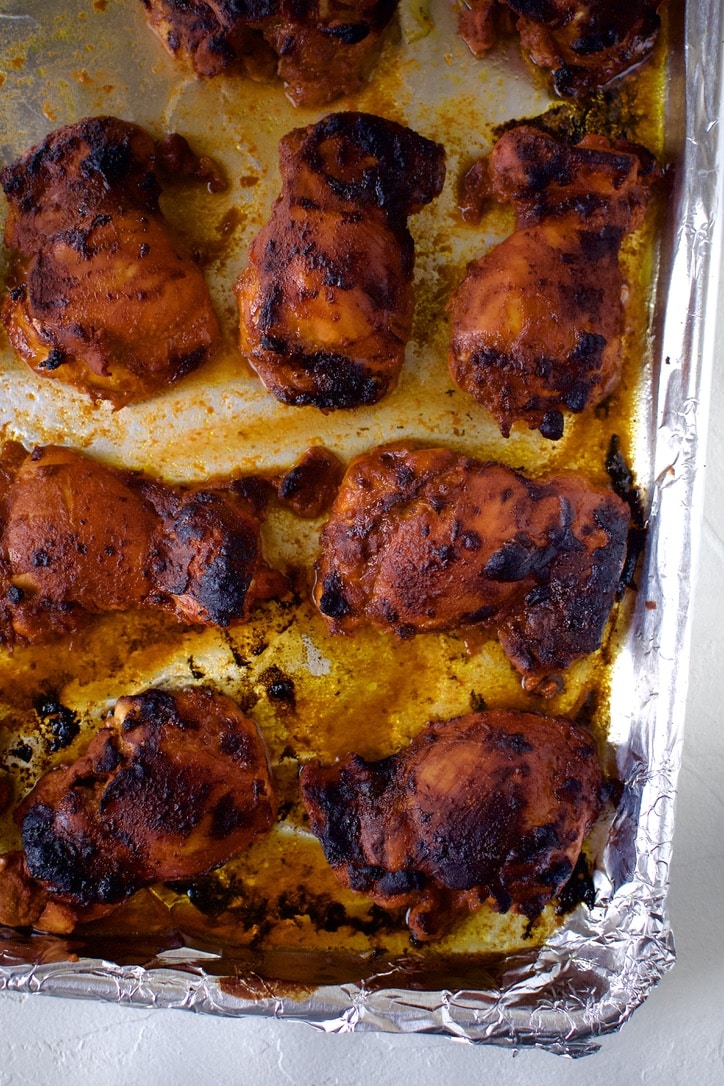 Marinated Chicken thighs on a foil lined sheet pan just after cooking.