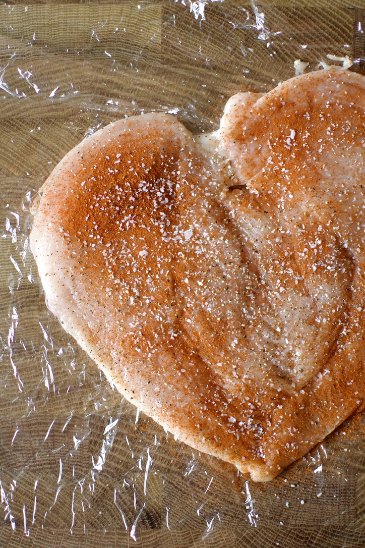 A split, tenderized, and seasoned, chicken breast.