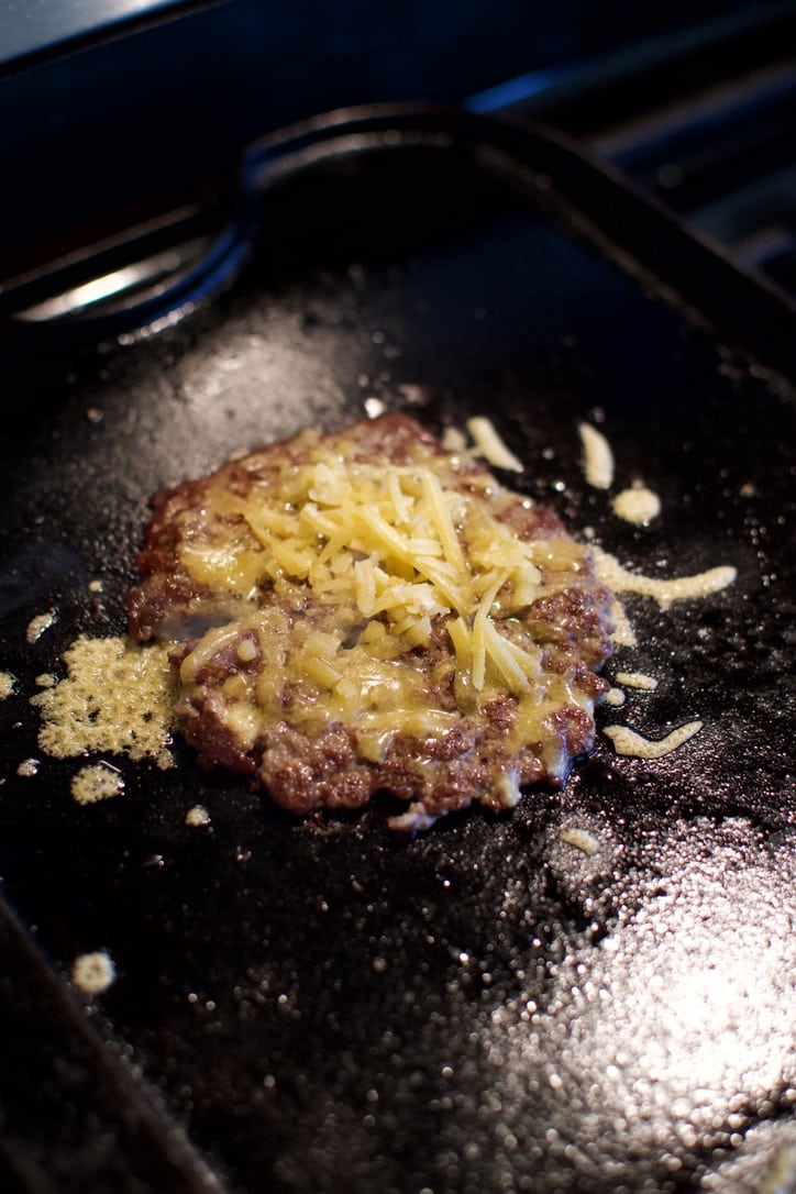 Melting cheese on a cooked burger patty.
