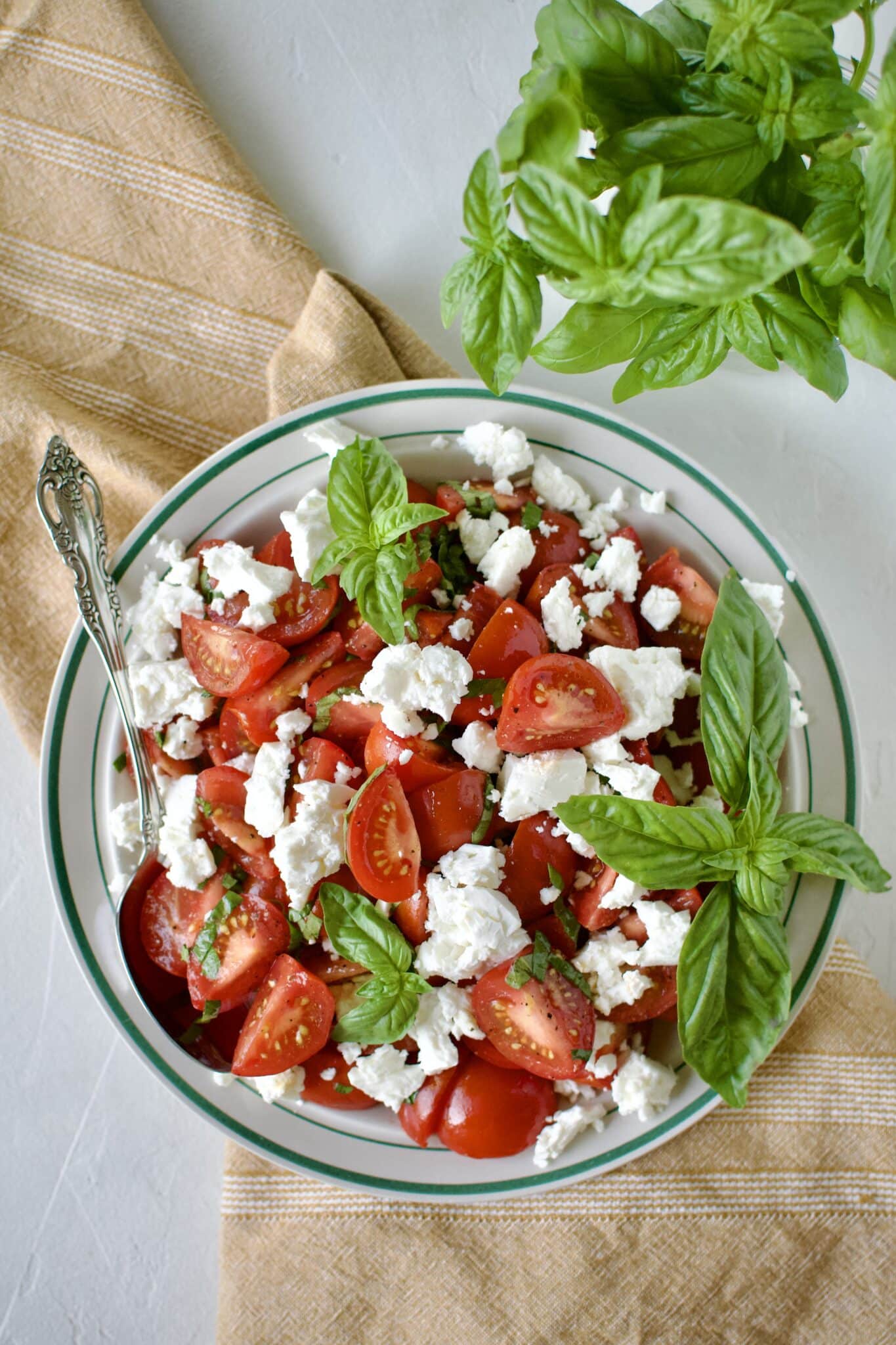 Tomato Feta Salad on a serving platter, garnished with big basil leaves.