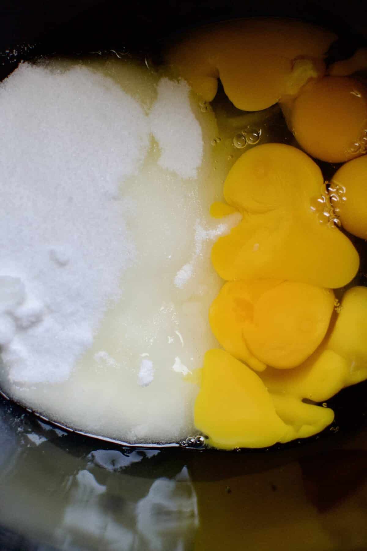 Eggs and Sugar in the bowl of a stand mixer ready to be whipped.
