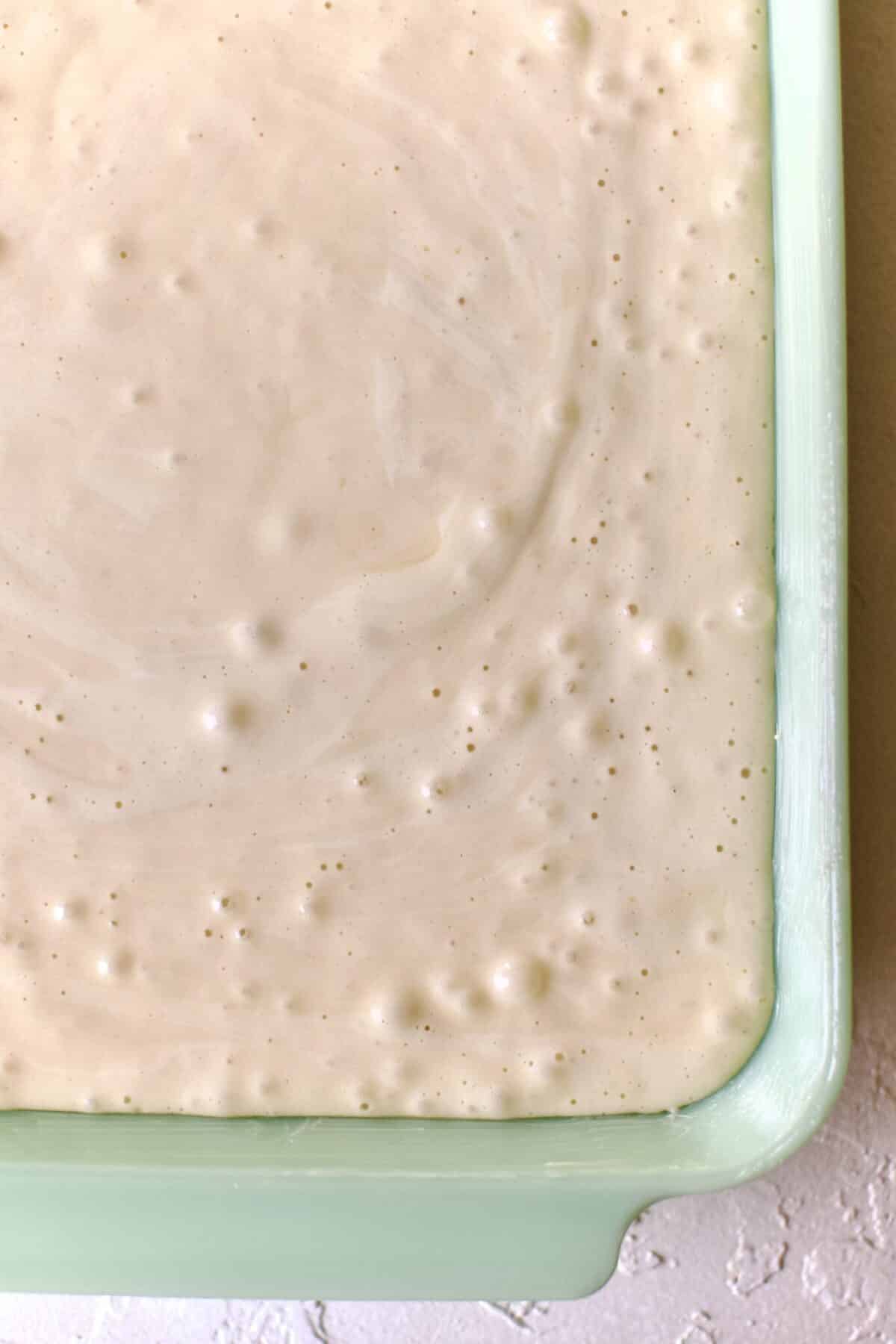 Tres leches cake batter in a buttered baking dish.