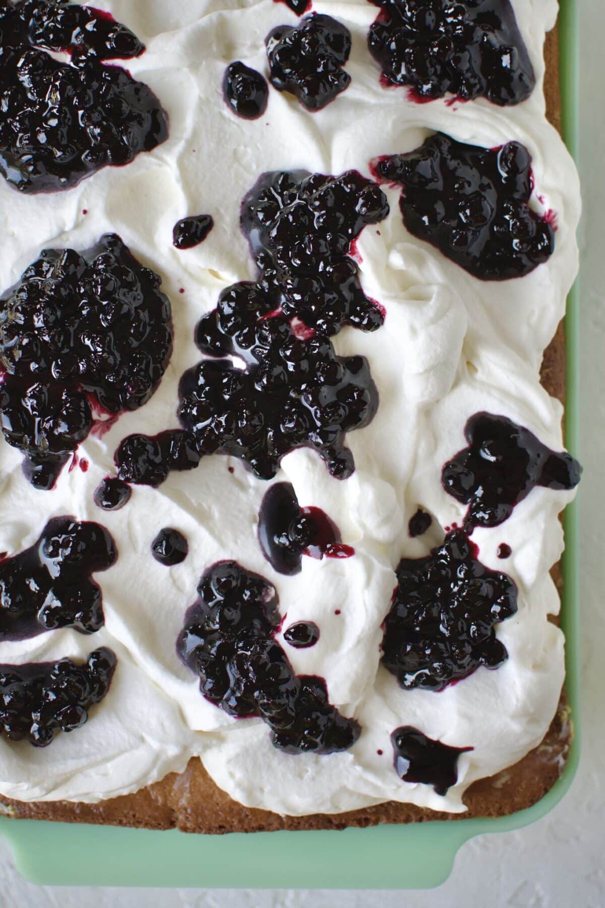 dropping dollops of blueberry jam on top of the whipped cream on the tres leches cake.