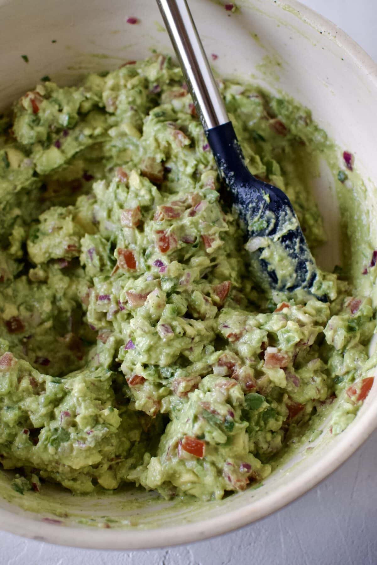 Freshly smashed and mixed guacamole in a large bowl.