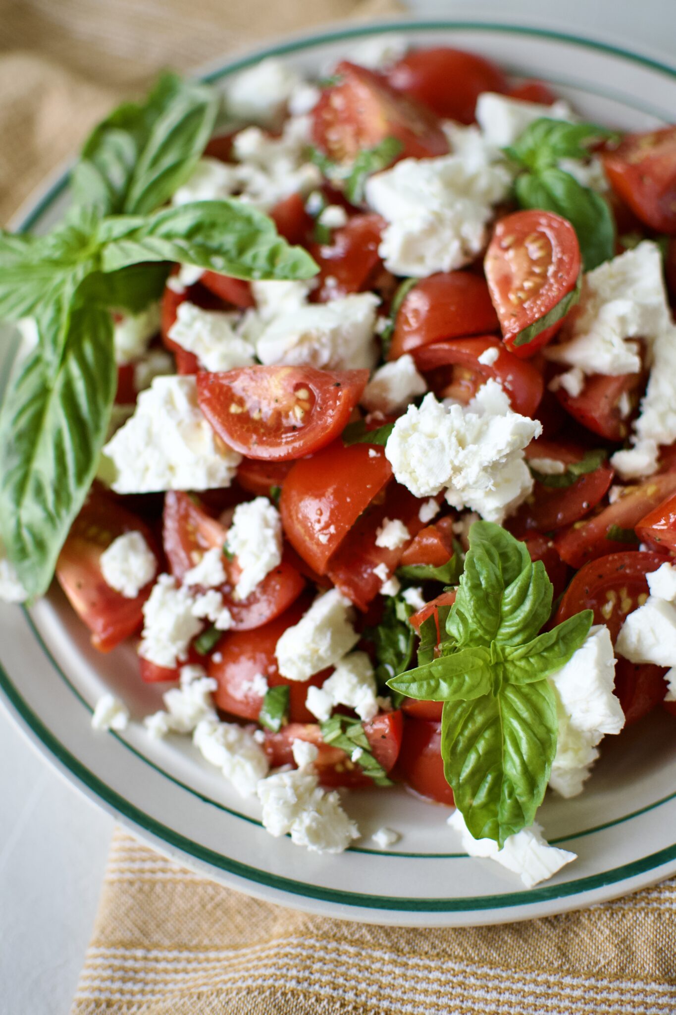 Tomato Feta Salad on a serving platter, garnished with big basil leaves.