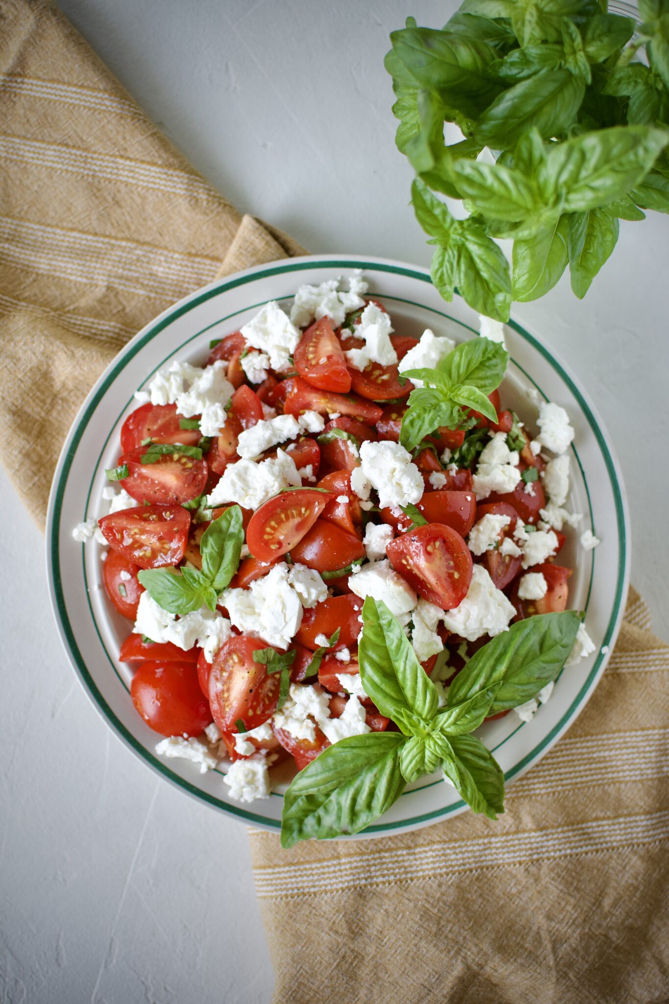 Tomato Feta Salad on a serving platter, garnished with big basil leaves.