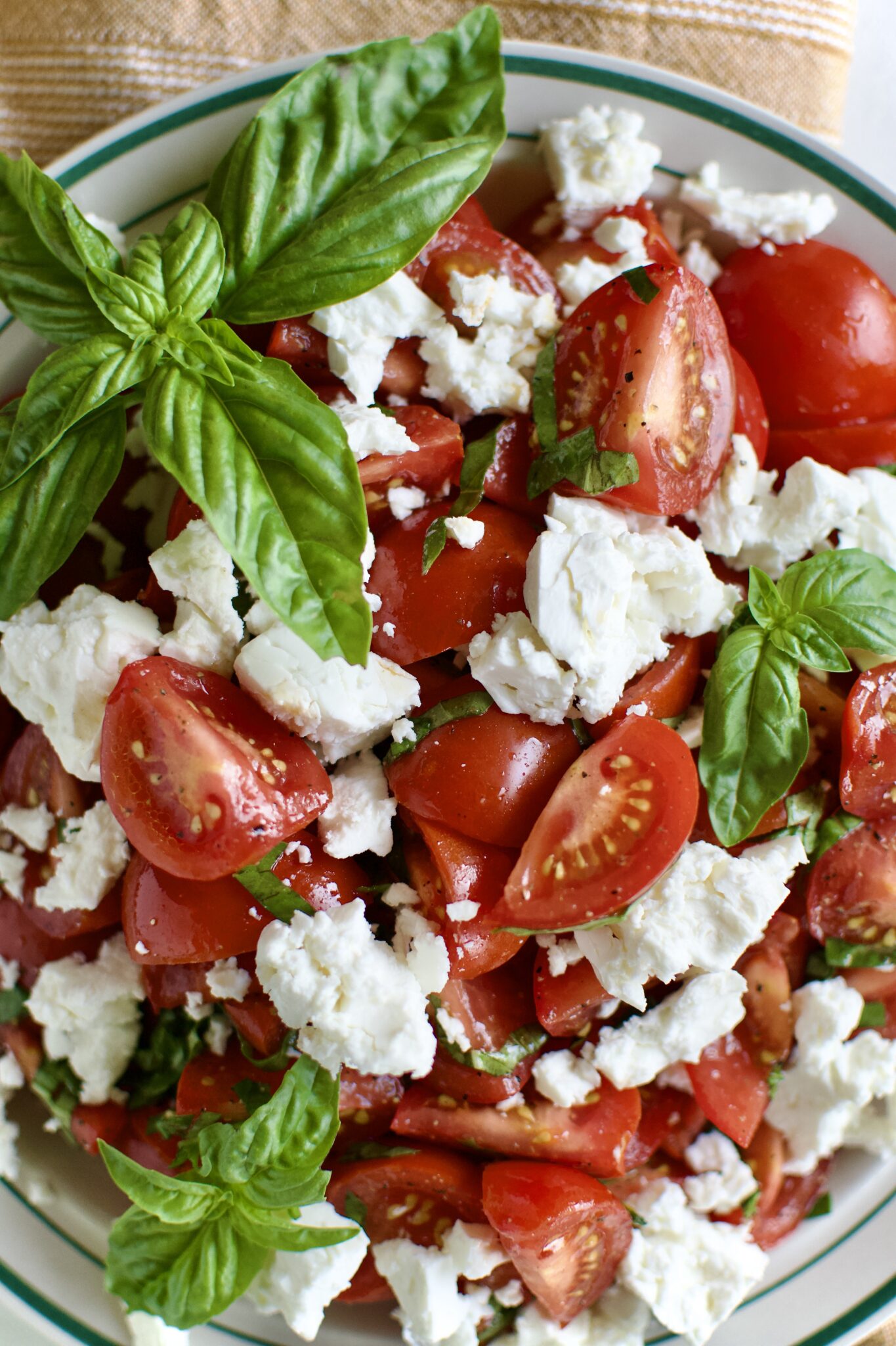 Tomato Feta Salad on a serving platter, garnished with big basil leaves.