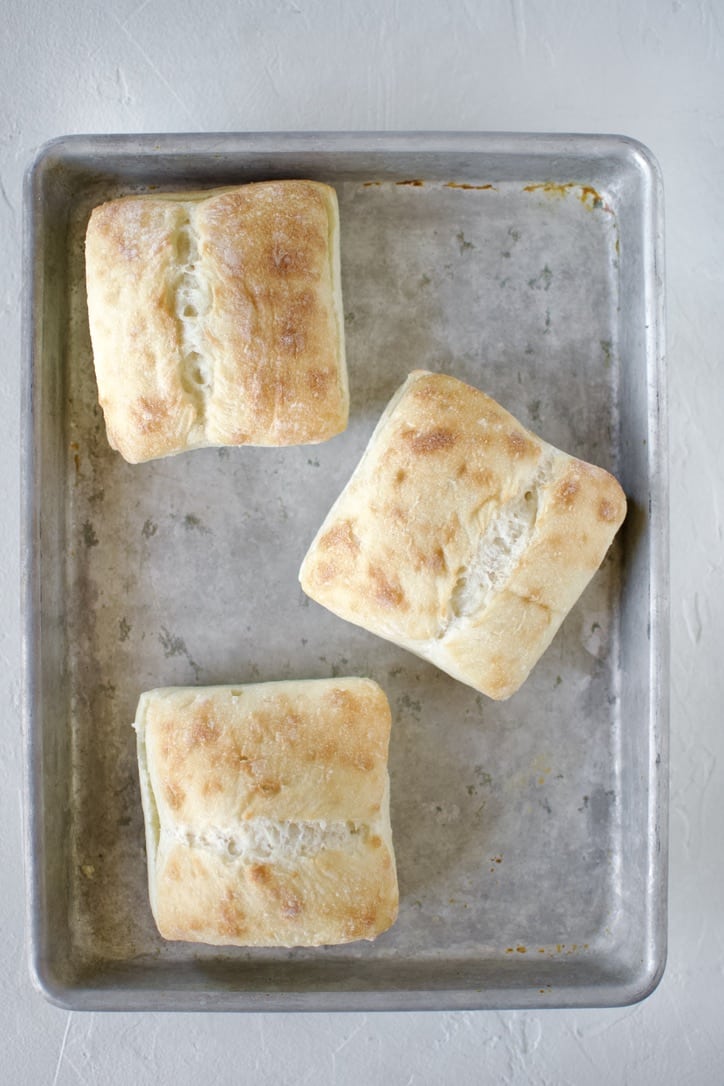 Ciabatta rolls on a sheet tray.