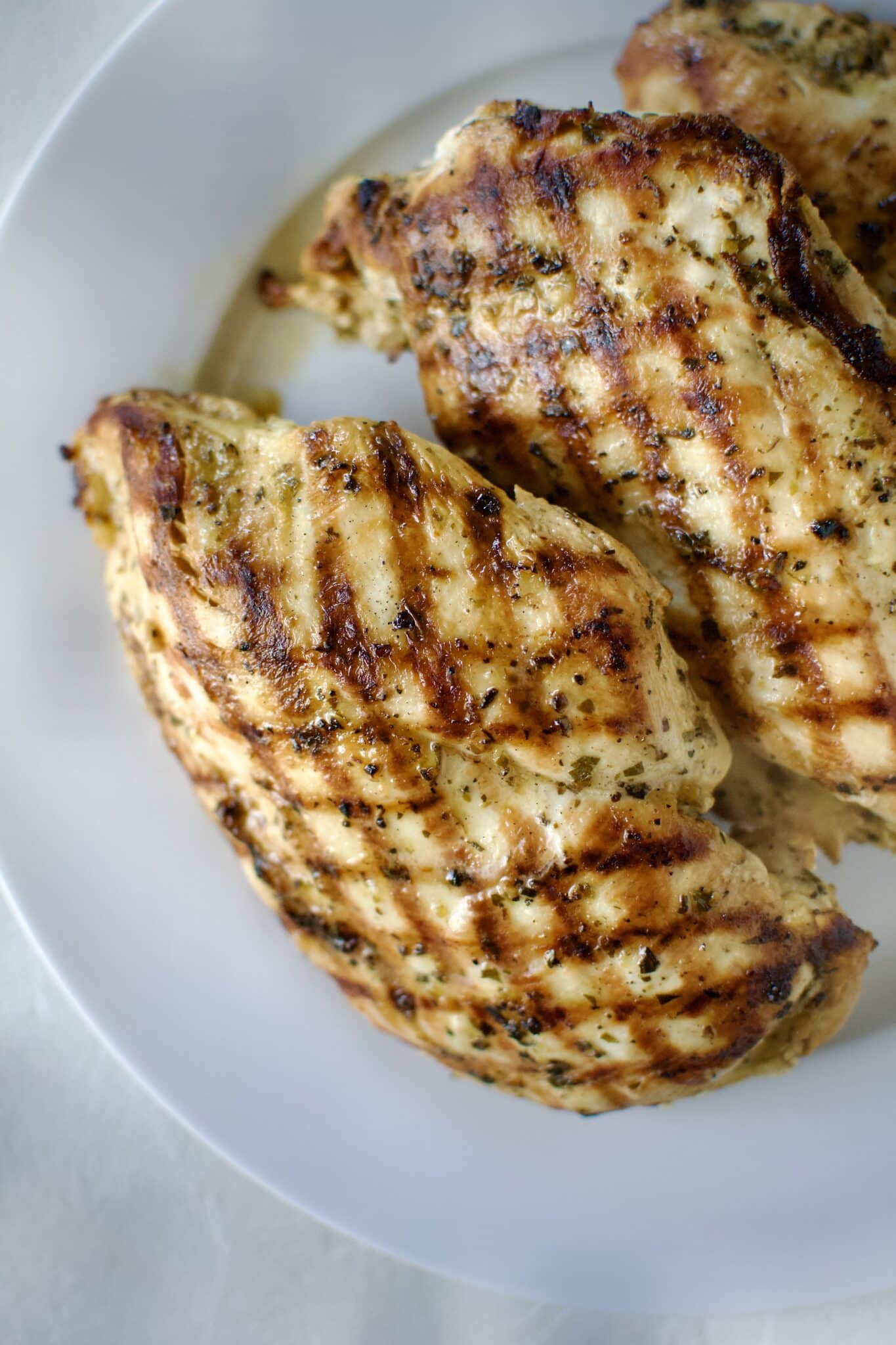 Italian Marinated chicken that has been grilled and is resting on a palate.
