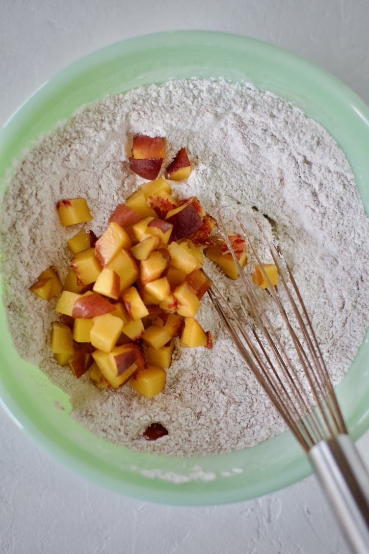 Adding diced peaches to the mixed dry pancake mix.