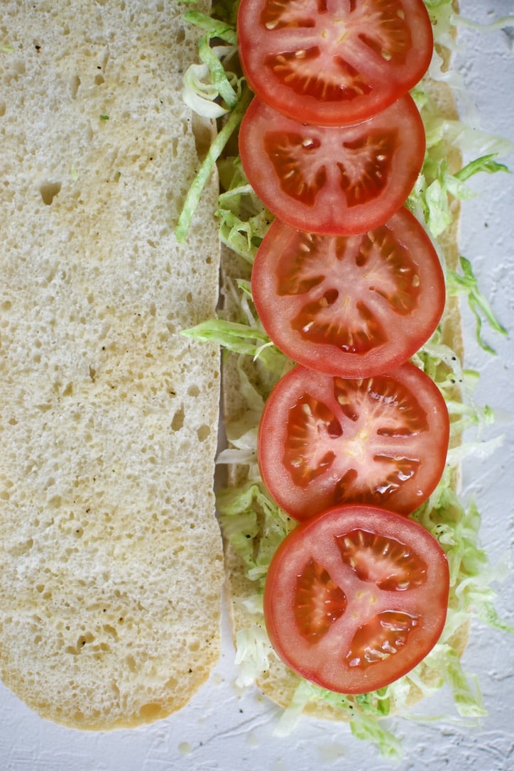 Adding the tomatoes to the Italian Sub.