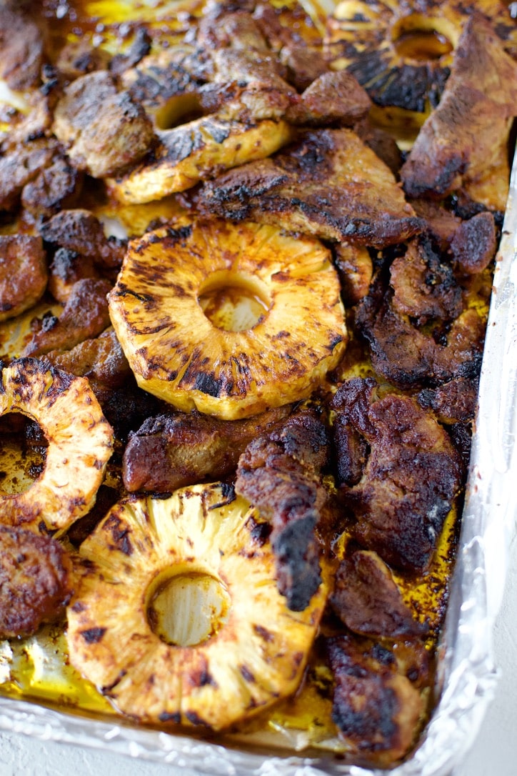 Marinated pork, and cut pineapple, on a sheet pan, after roasting.