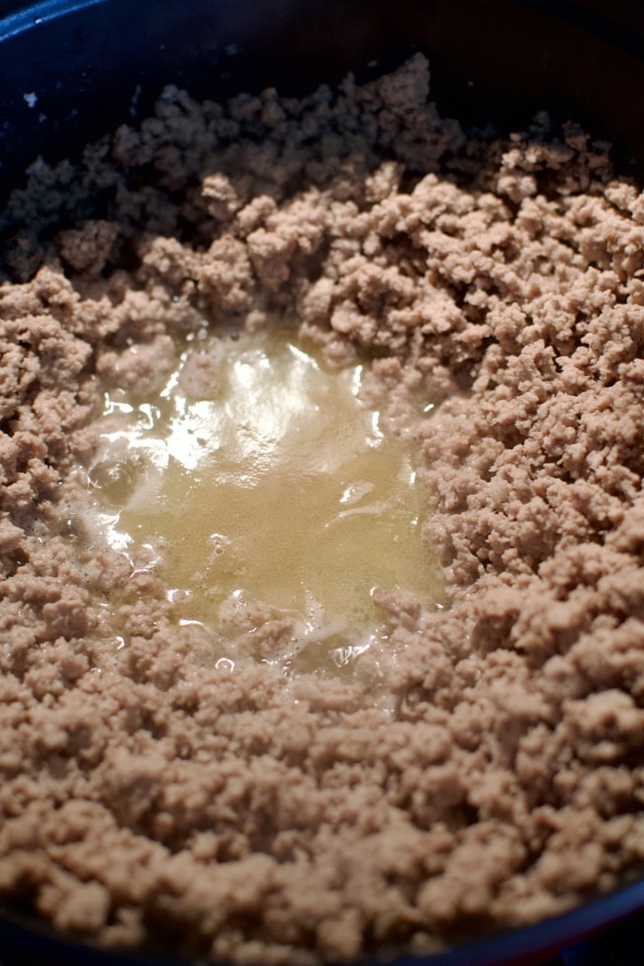 Browned ground turkey in a large pot, before draining off the excess liquid.