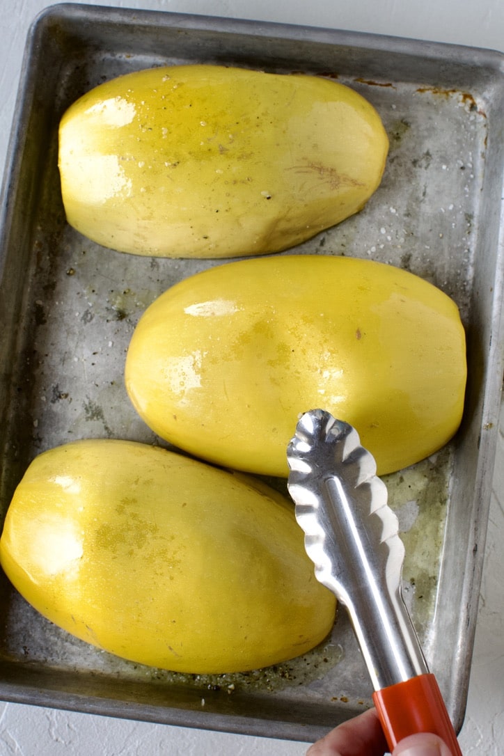 Roast Spaghetti Squash, after cooking, testing for doneness by pressing the skin. It is done when it leaves a dent, as seen.