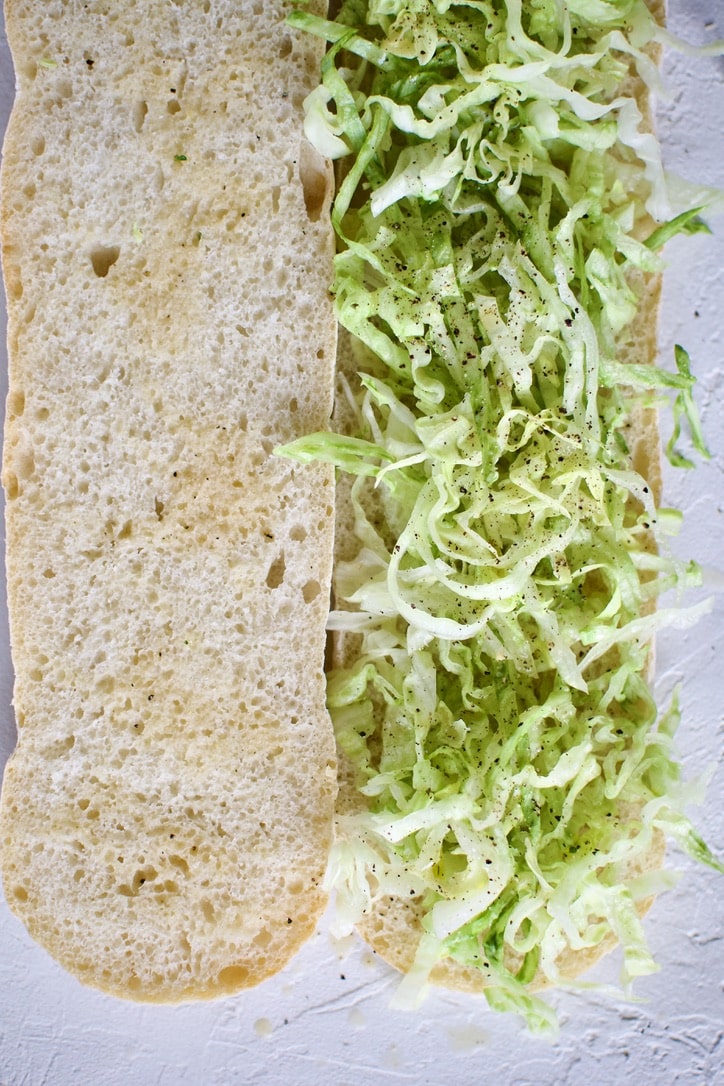 Layer one of the Italian Subs Recipe, open the bread and add lettuce and lots of italian vinaigrette. 