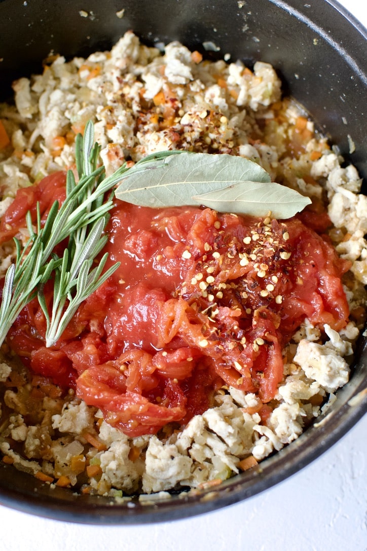 Tomatoes, herbs and seasonings added to the pot.