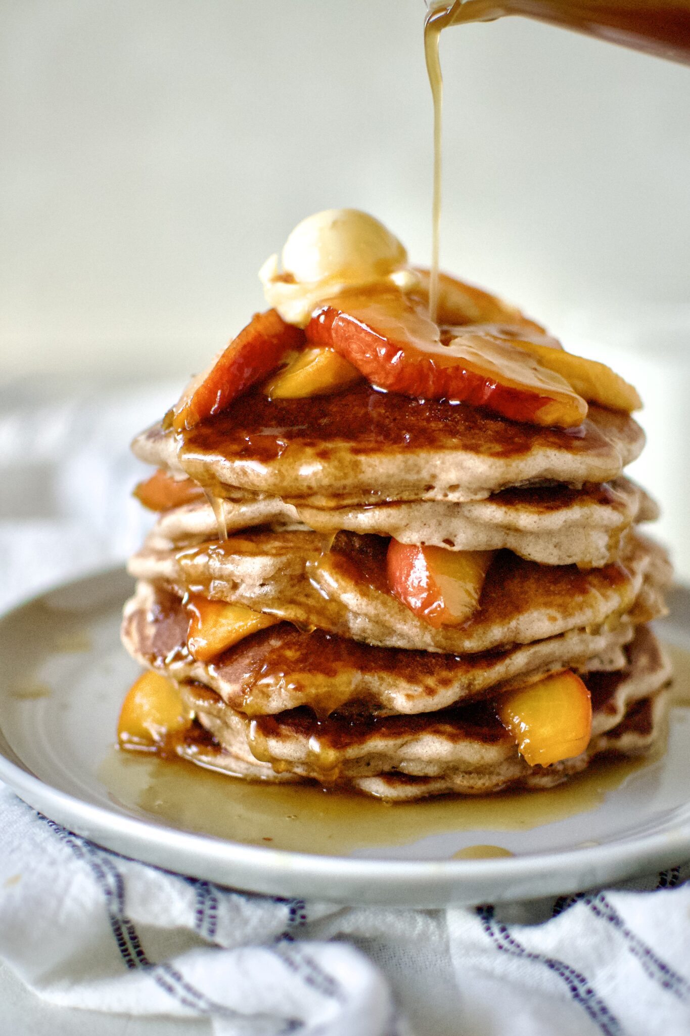 Peach Pancakes onPeach Pancakes on a plate ready to eat. Drizzling with syrup. a plate ready to eat.