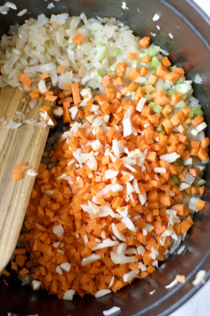 Adding the carrots, celery, and garlic to the pot.