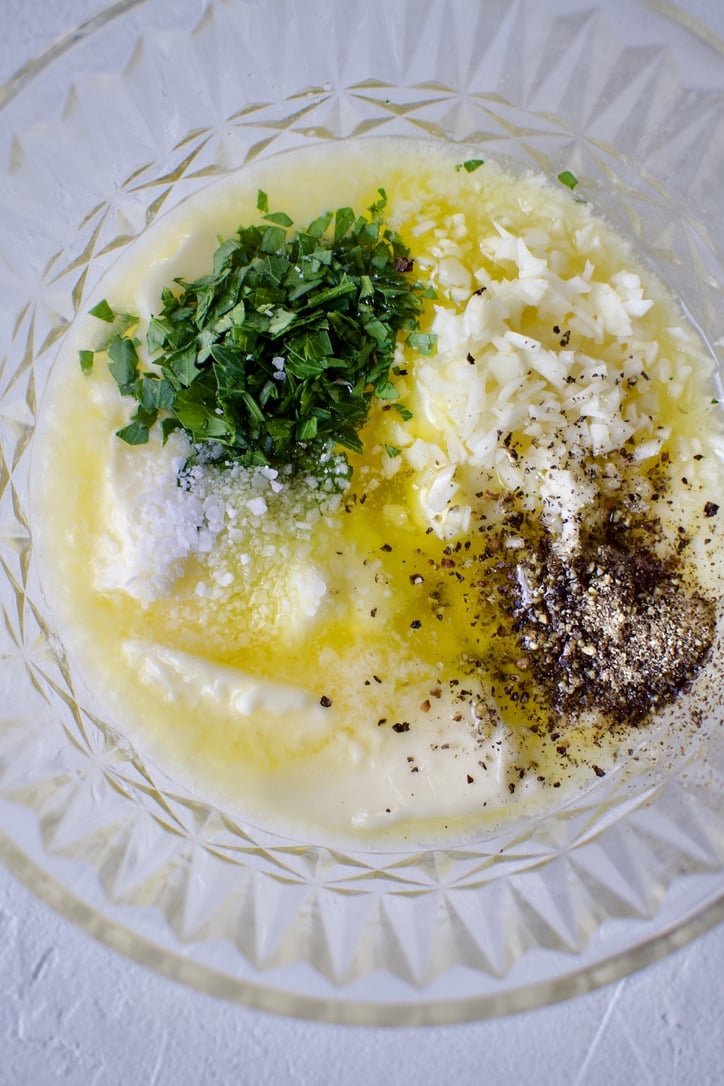 Adding garlic, salt, pepper, and parsley to nearly melted butter.