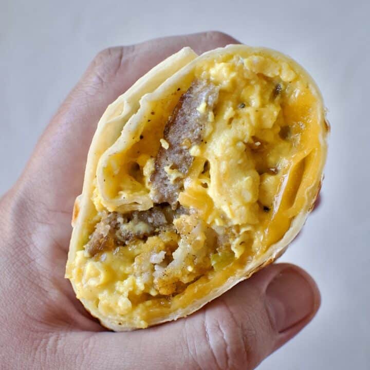 Half a breakfast burrito in hand ready to eat.