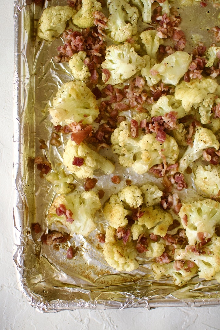Cauliflower florets after roasting, adding bacon bits to the pan.