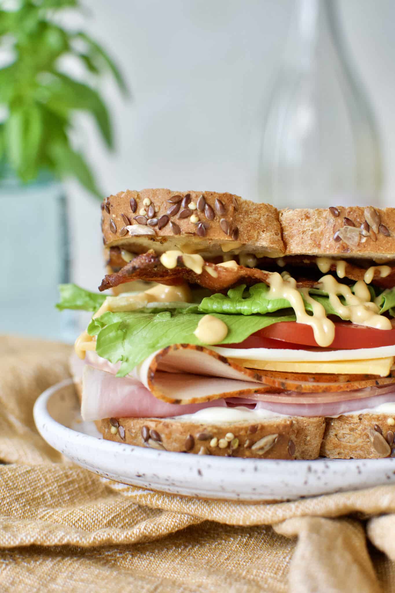 Club Sandwich Recipe on a plate served with a glass of rosé behind it.