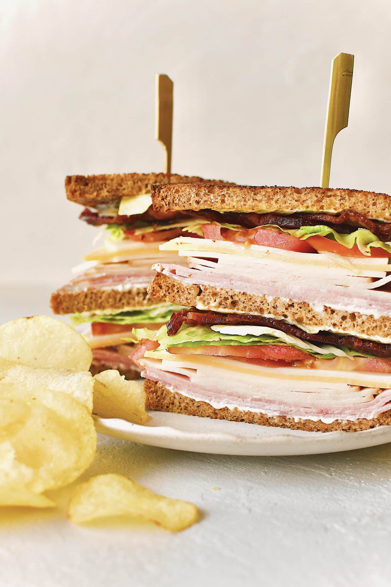 Double Decker Club Sandwich Recipe on a plate with chips.