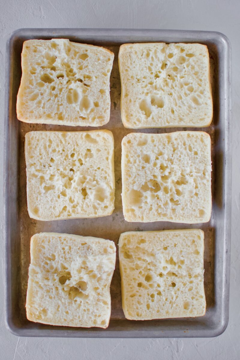 Opened Ciabatta rolls on a sheet tray.