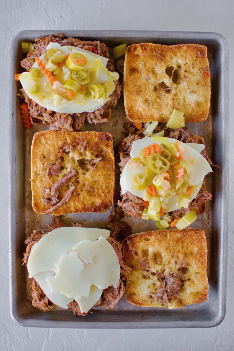 Italian Beef added to toasted ciabatta rolls, topped with cheese and giardiniera.
