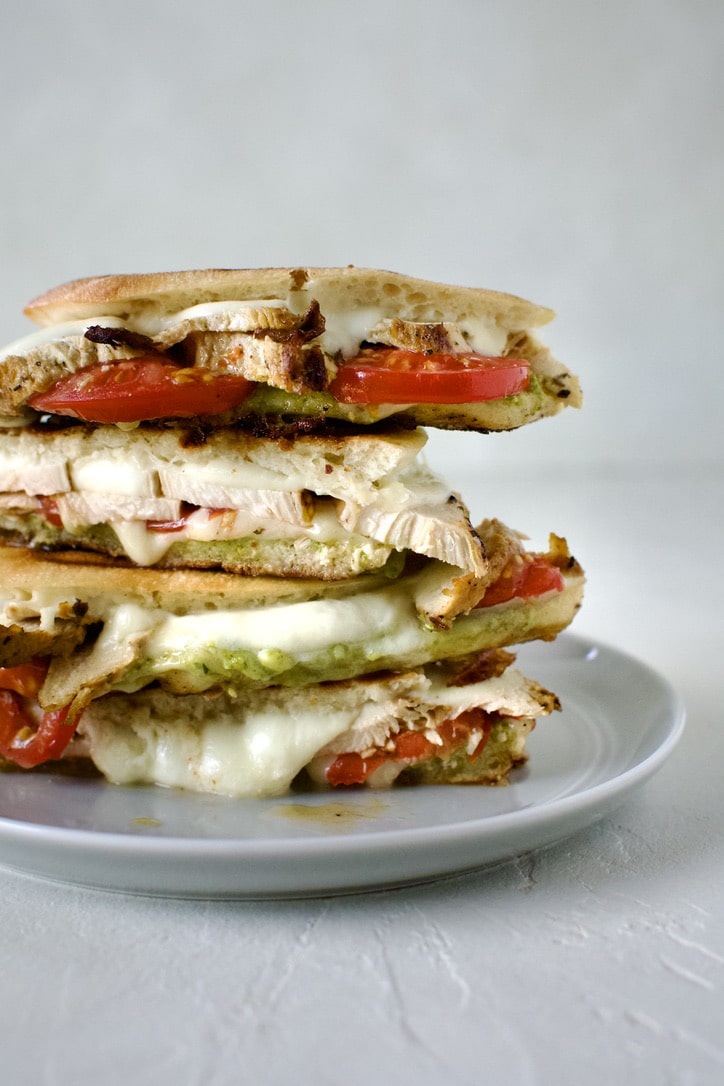 Pesto Chicken Panini, sliced and stacked on a plate, ready to eat.