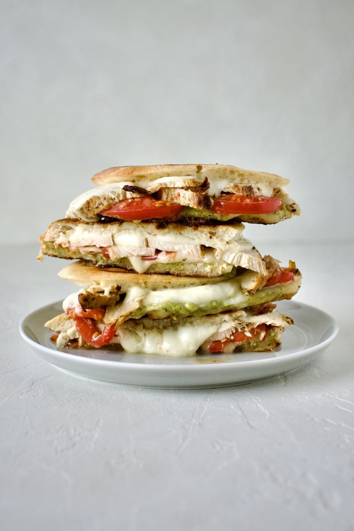 Pesto Chicken Panini, sliced and stacked on a plate, ready to eat.