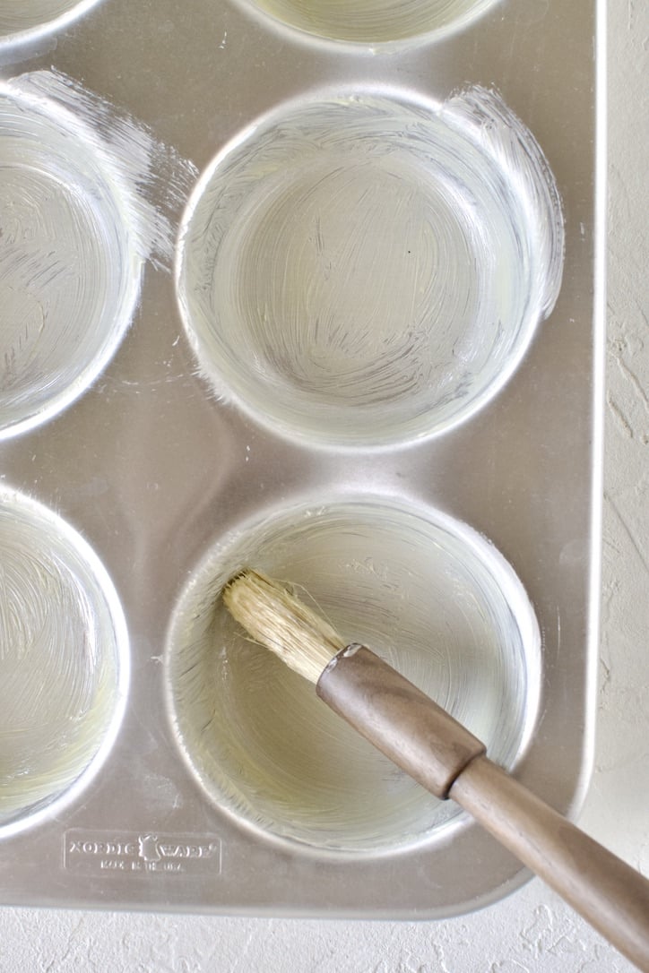 Buttering a jumbo muffin tin.