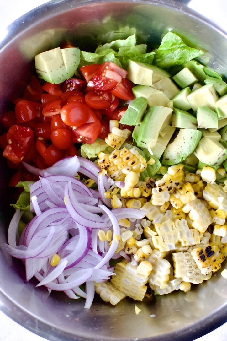 Salad ingredients added to a bowl ready to be mixed up.