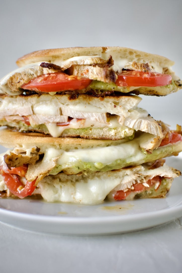 Pesto Chicken Panini, sliced and stacked on a plate, ready to eat.