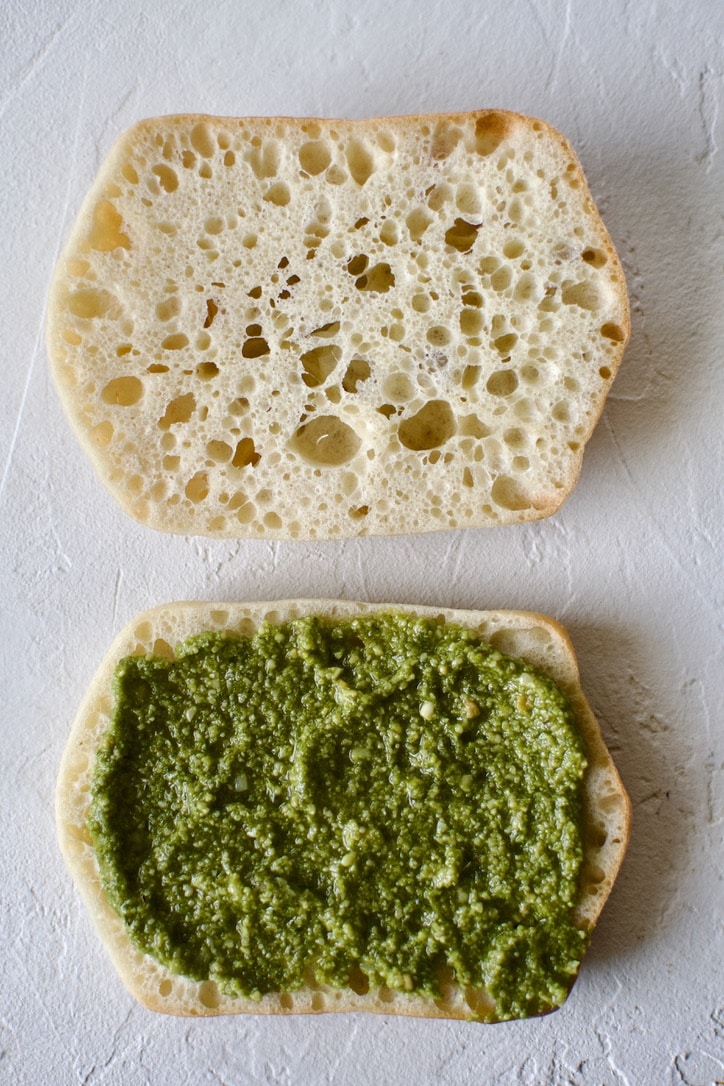 Building the panini, bread sliced open, pesto added.