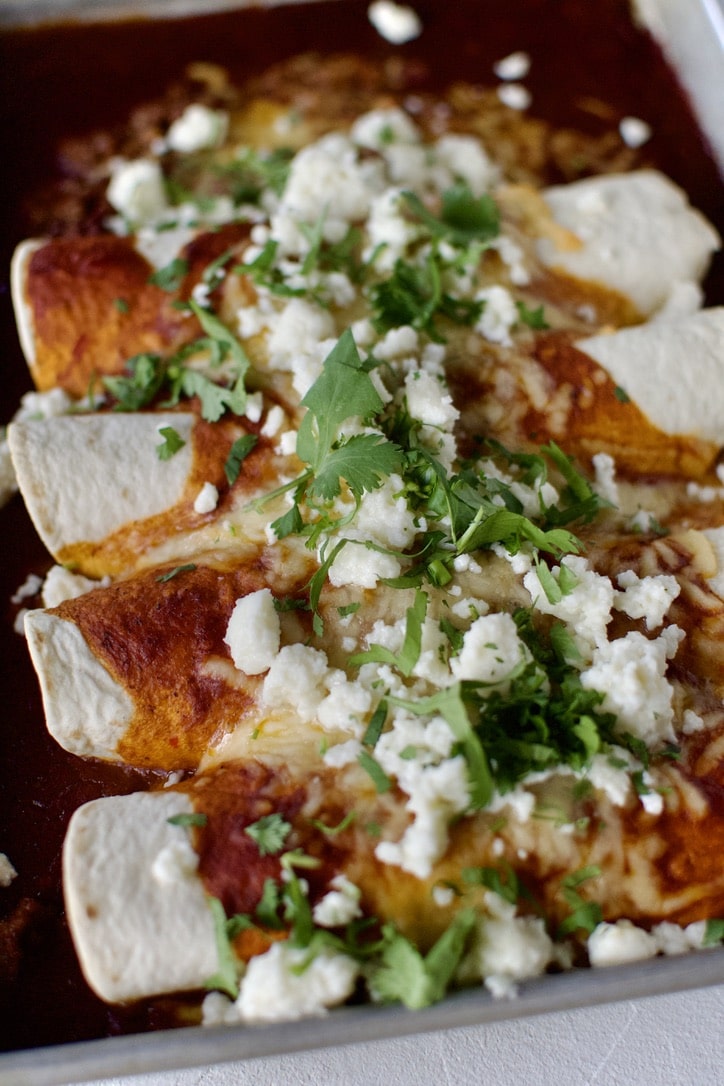 Ground Beef Enchiladas, ready to eat, topped with queso fresco and cilantro.