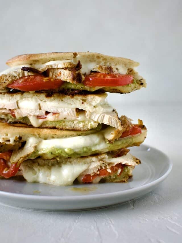 Pesto Chicken Panini, sliced and stacked on a plate, ready to eat.