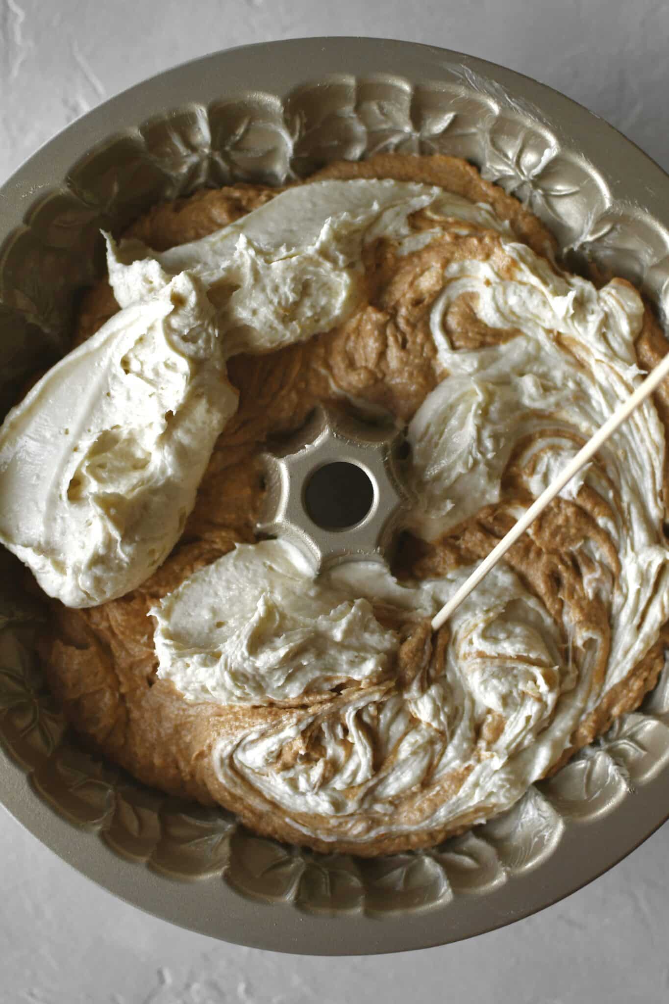 Swirling the first layer of plain and pumpkin cake together in the pan.