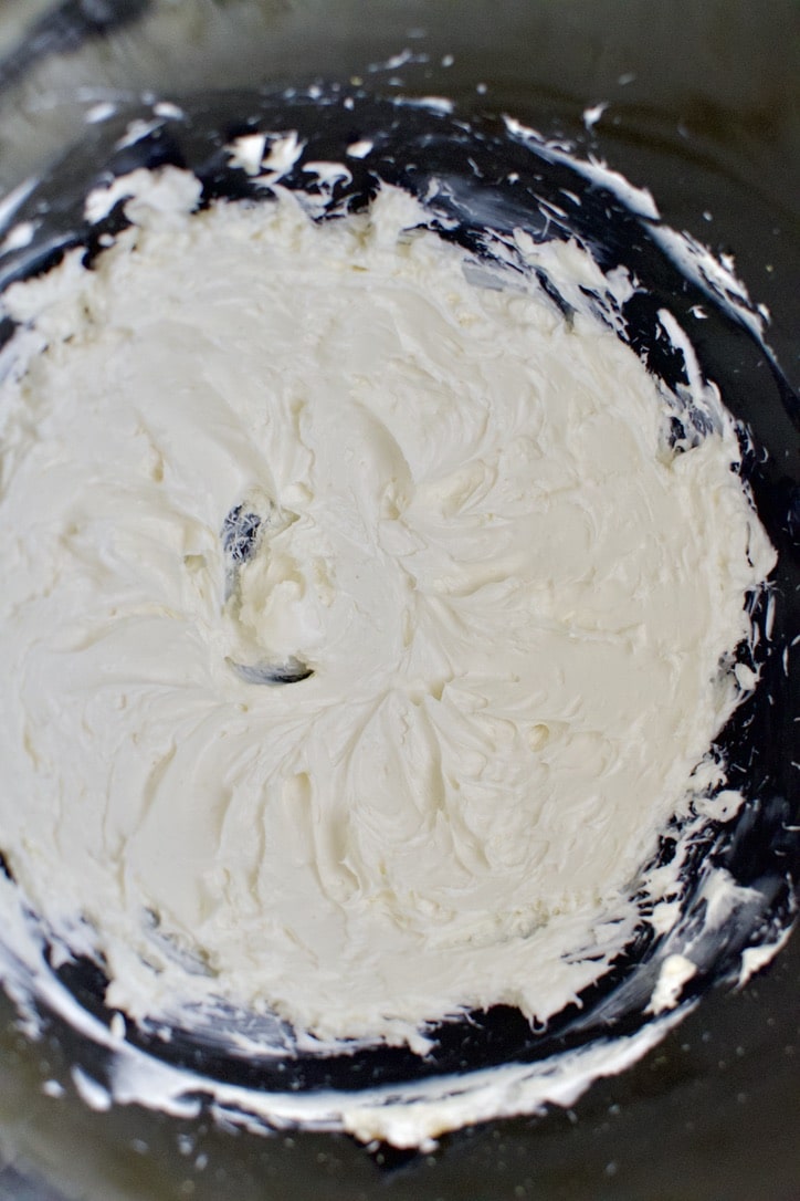 Cream Cheese whipped in the bowl of a stand mixer.