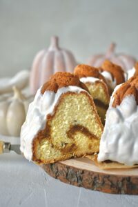Pumpkin Pound Cake with a slice being removed from the bundt that looks like pumpkins in a field.
