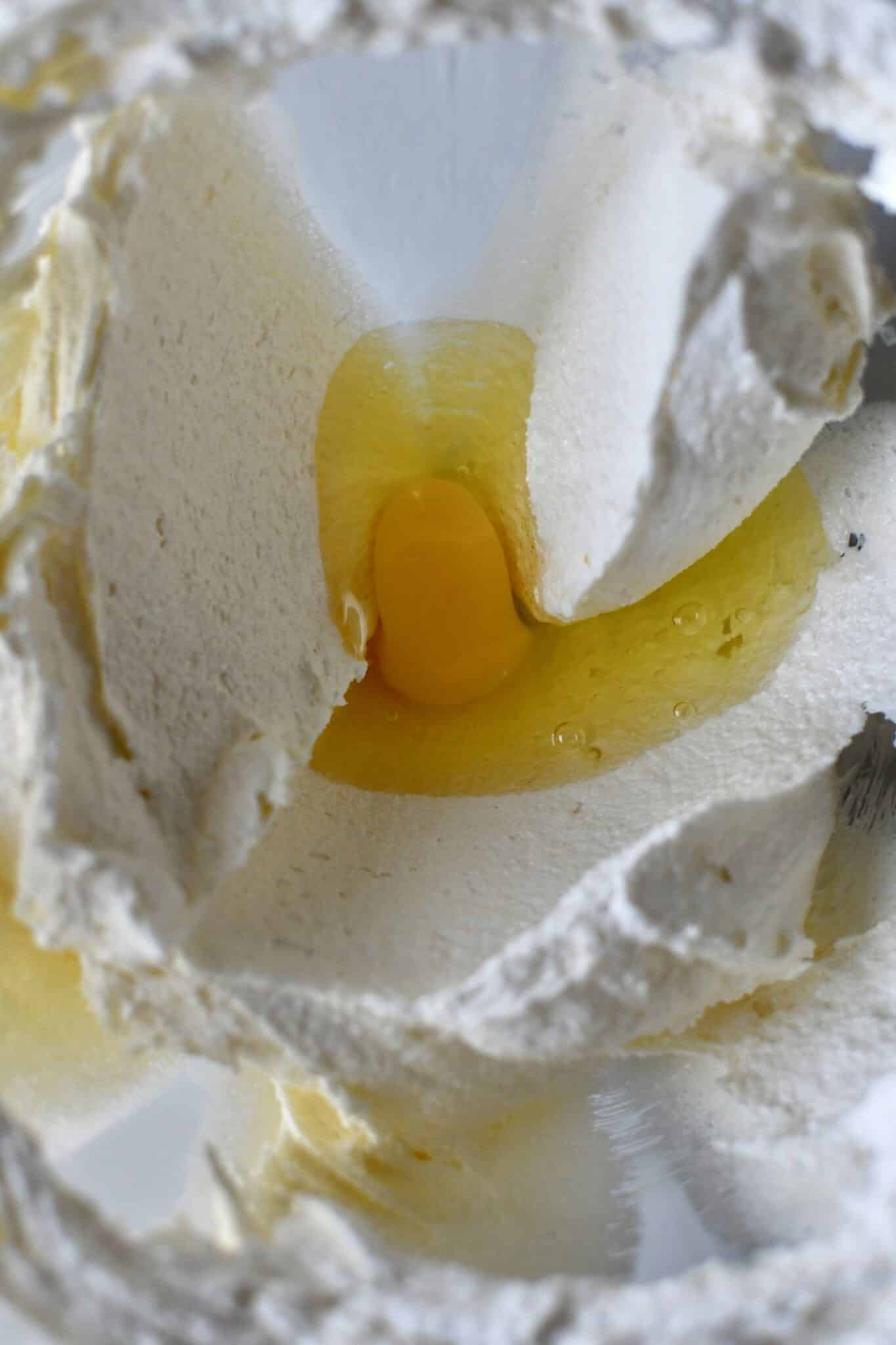 Wet ingredients for pound cake creamed together in a stand mixer bowl. Adding the egg.