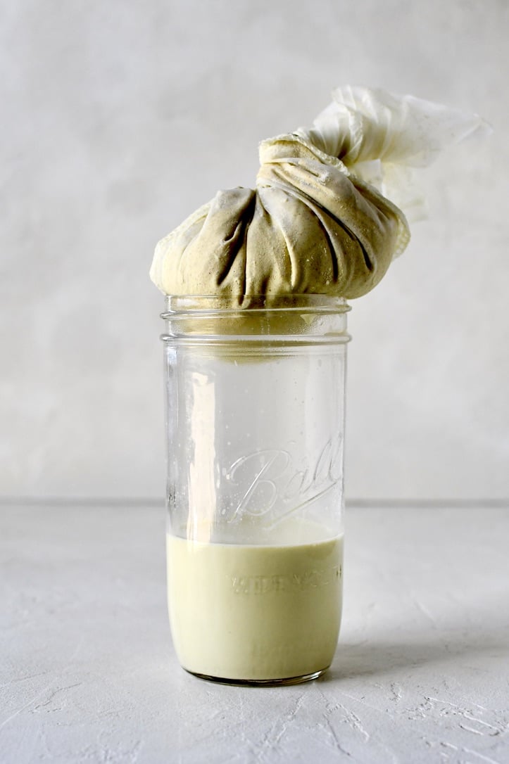 Straining pistachio milk through a nut milk bag.