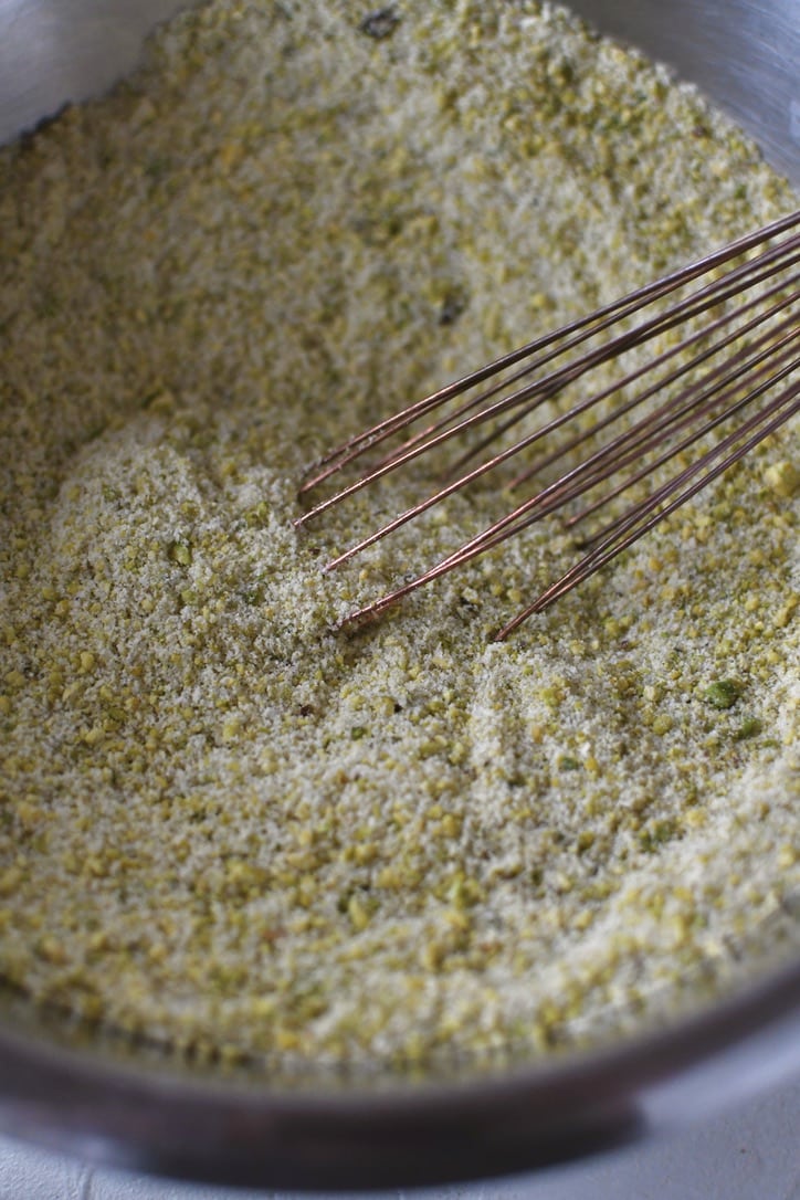 Pistachio and almond flours in a bowl, whisked together with granulated sugar.